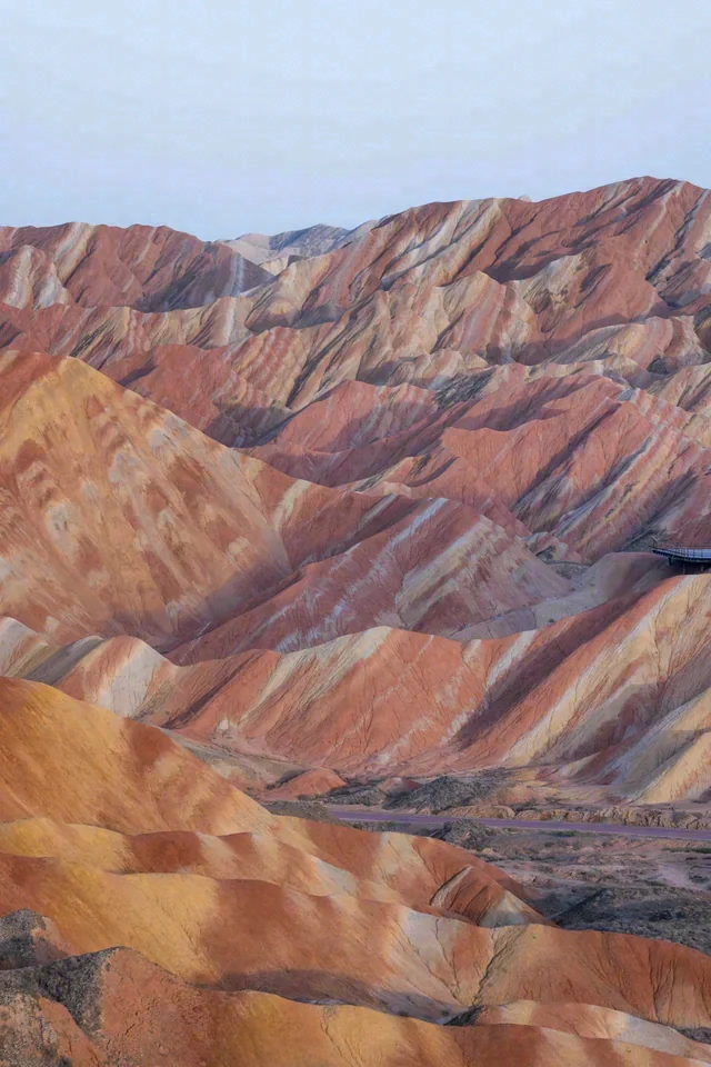 Bands of orange, yellow and muted red cross an eroded rocky landscape.
